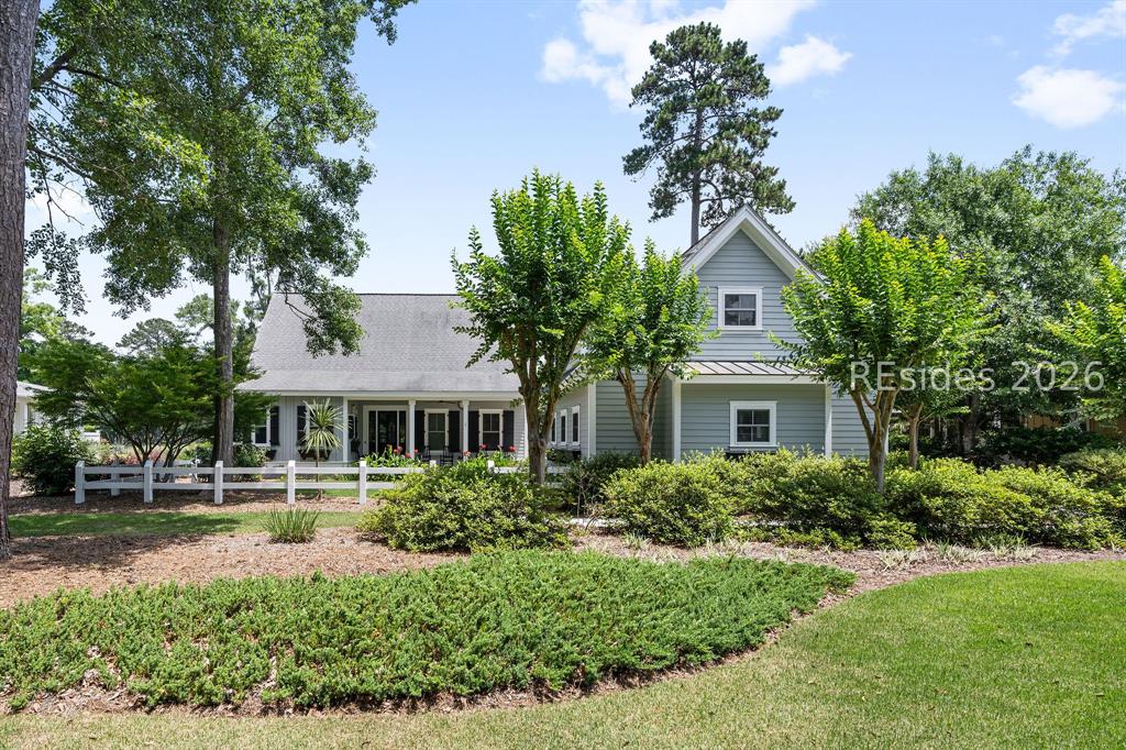 Light blue Lowcountry home with white porch and mature trees on a manicured lot