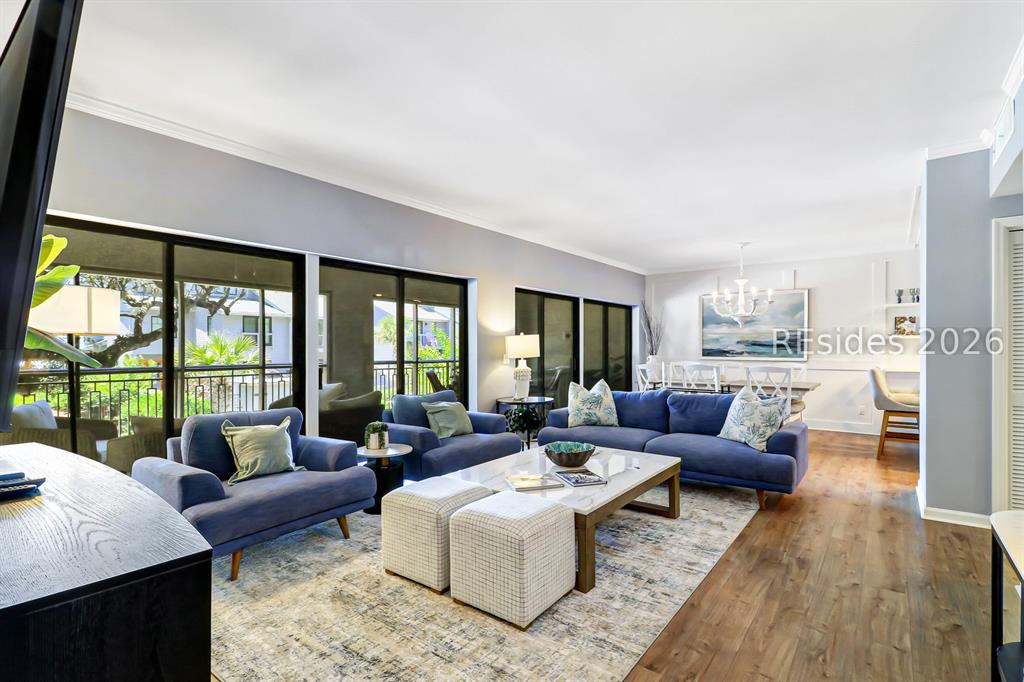 Bright open-concept living room with navy sofas and screened porch overlooking Sea Pines